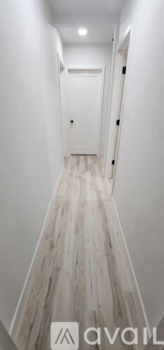 A long hallway with white walls and wood flooring.