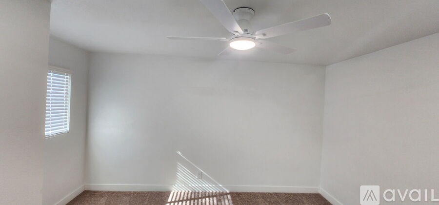 A room with a ceiling fan and a window with blinds.