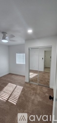 A room with a carpeted floor and a ceiling fan.