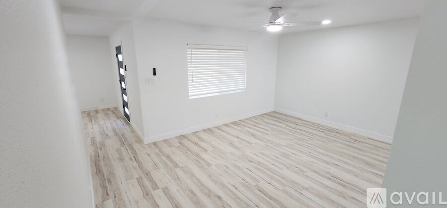 A spacious room with wooden flooring and white walls.