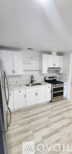 A kitchen with white cabinets and a wooden floor.