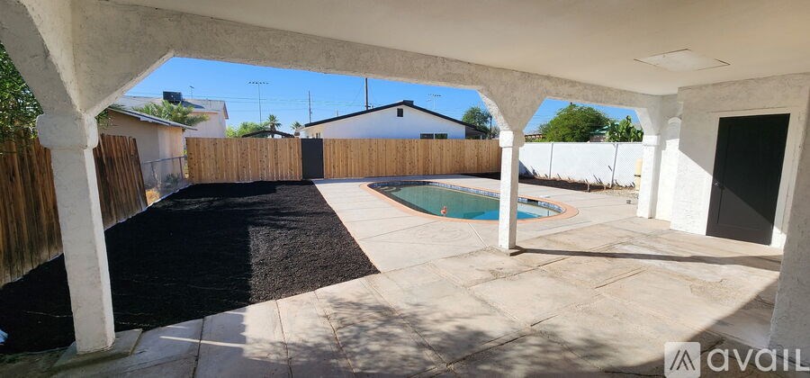 A patio with a black carpet and a pool in the backyard.