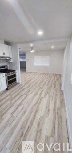 A spacious room with wooden flooring and white walls.