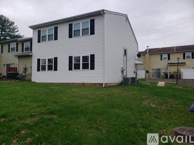 A white house with a grey roof and a green lawn in front.