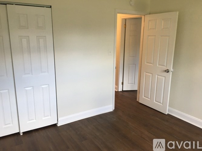 A room with two white doors and wooden floors.