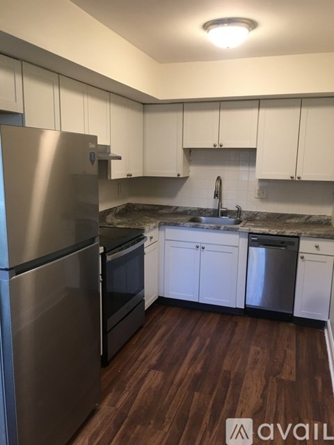 A kitchen with a stainless steel refrigerator and wooden floors.
