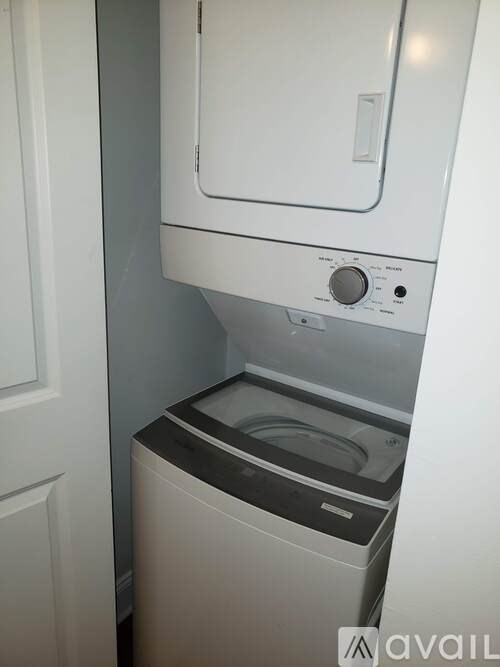A white dishwasher with a black control panel is installed in a narrow space.