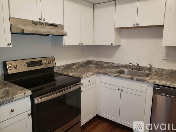 A kitchen with a black stove top oven and white cabinets.