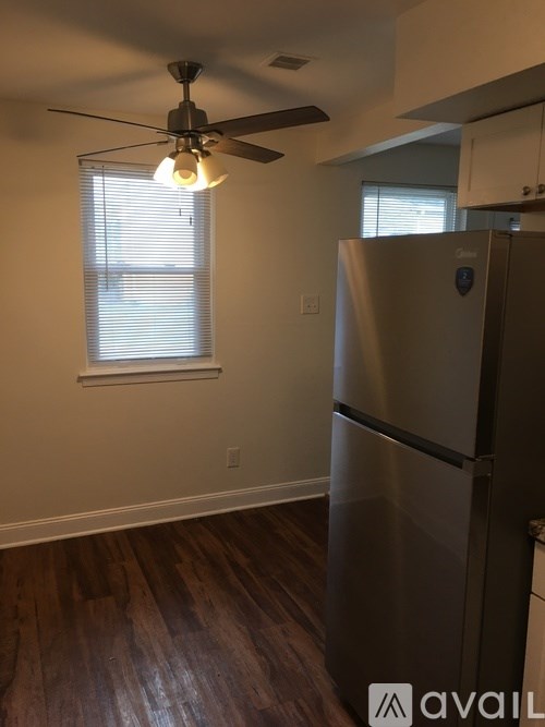 A kitchen with a stainless steel refrigerator and wooden floors.