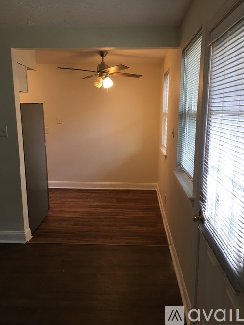 A room with a ceiling fan and wooden flooring.