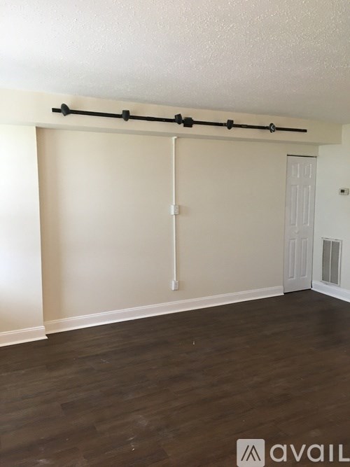 A room with a white door and a black bar on the wall.