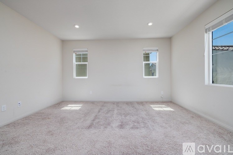 A spacious room with carpeted floor and two windows.