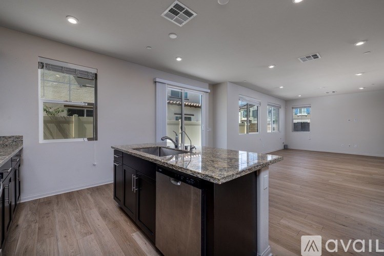 A modern kitchen with a granite countertop and wooden flooring.