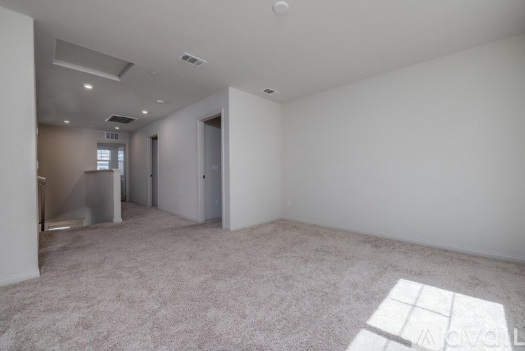 A large, empty room with a carpeted floor and white walls.