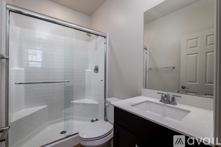 A bathroom with a white toilet, a sink, and a glass shower stall.
