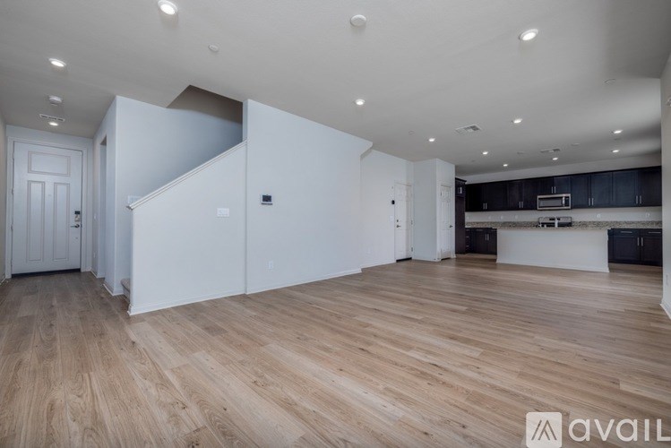 A spacious room with wooden flooring and white walls.