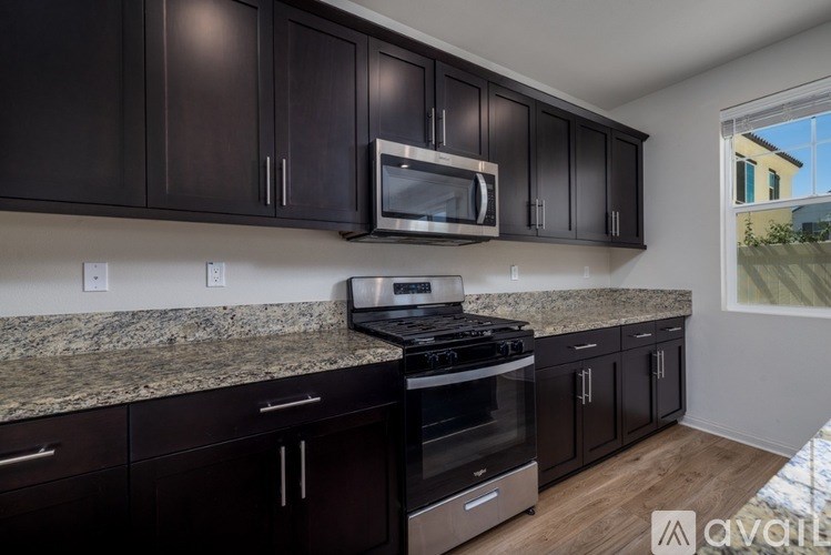 A kitchen with dark brown cabinets and granite countertops.
