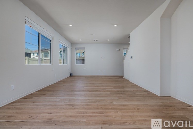 A spacious room with wooden flooring and white walls.