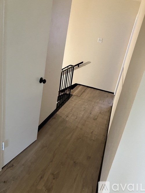 A hallway with a black railing and wooden floors.
