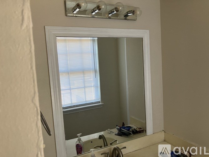 A bathroom with a mirror, sink, and light fixture.