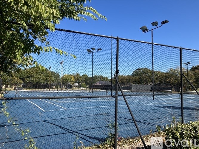A tennis court is surrounded by a fence and has a blue surface.