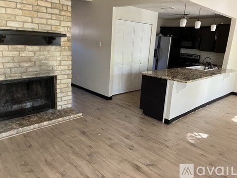 A kitchen area with a brick fireplace and a granite countertop.