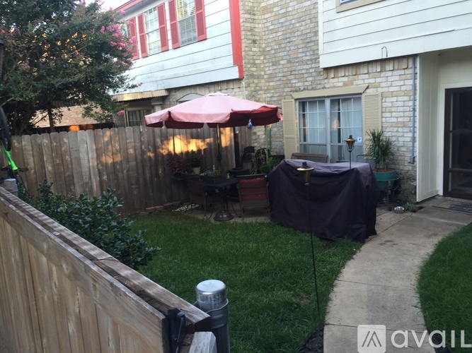 A patio with a red umbrella and a black tarp.