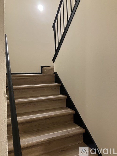 A staircase with wooden steps and a black railing.