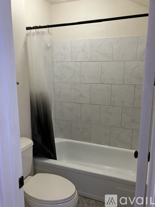 A white toilet sits next to a bathtub in a bathroom.