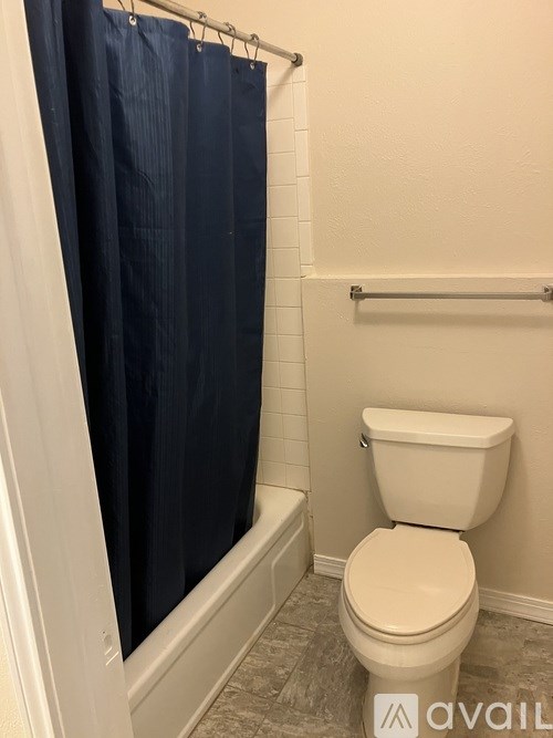 A white toilet in a bathroom with a blue shower curtain.