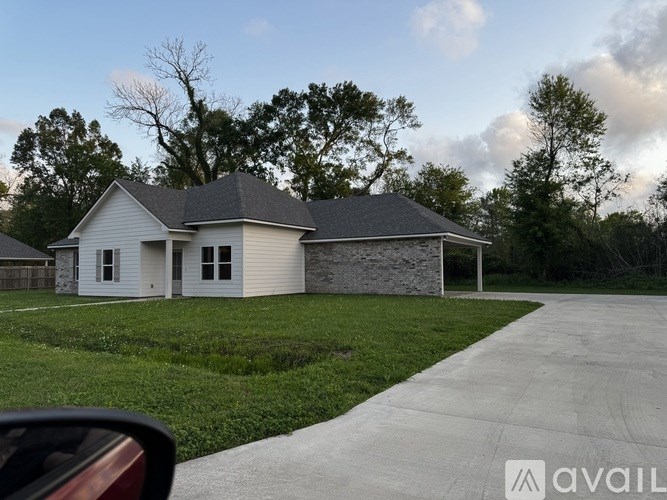 A house with a grey roof and a stone wall is available for sale.