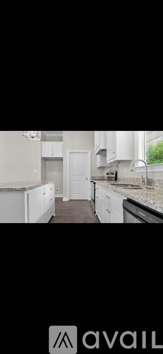 A kitchen with white cabinets and a black countertop.