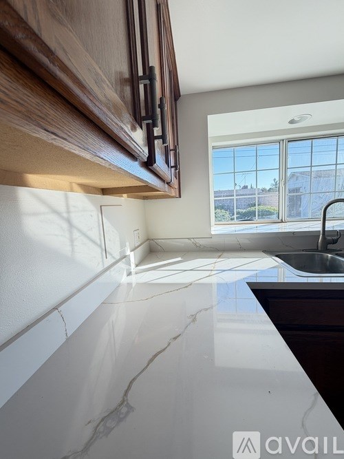 A kitchen with a marble countertop and wooden cabinets.