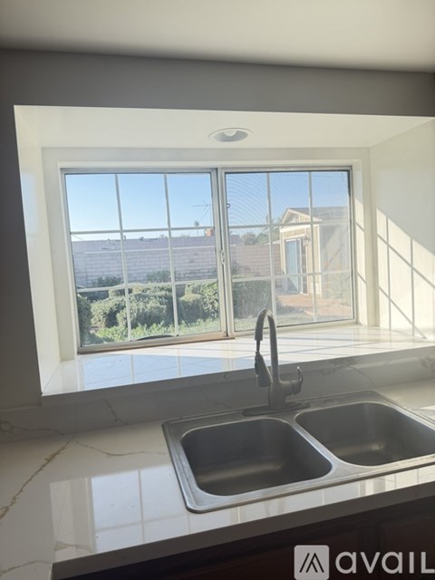 A kitchen with a double sink and a window overlooking a residential area.
