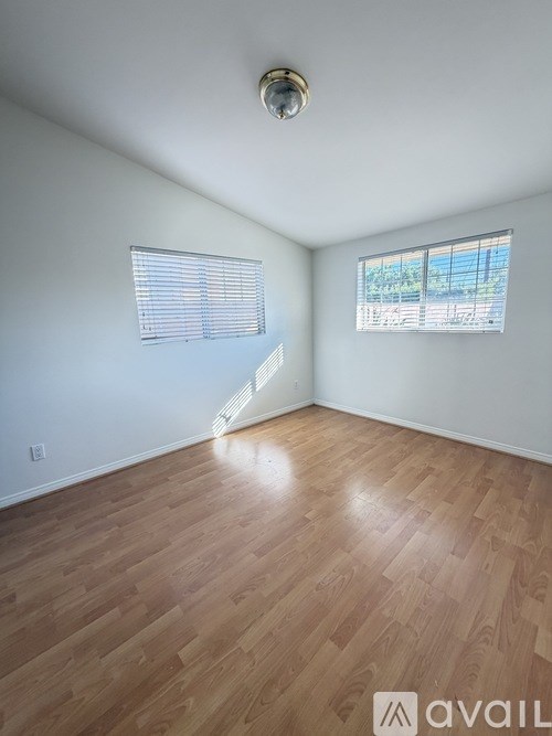 A room with wooden flooring and a window with blinds.