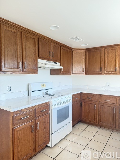 A kitchen with wooden cabinets and a white stove top oven.