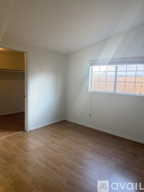 A room with wooden flooring and a window with blinds.