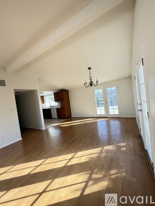A large empty room with wooden floors and a chandelier.
