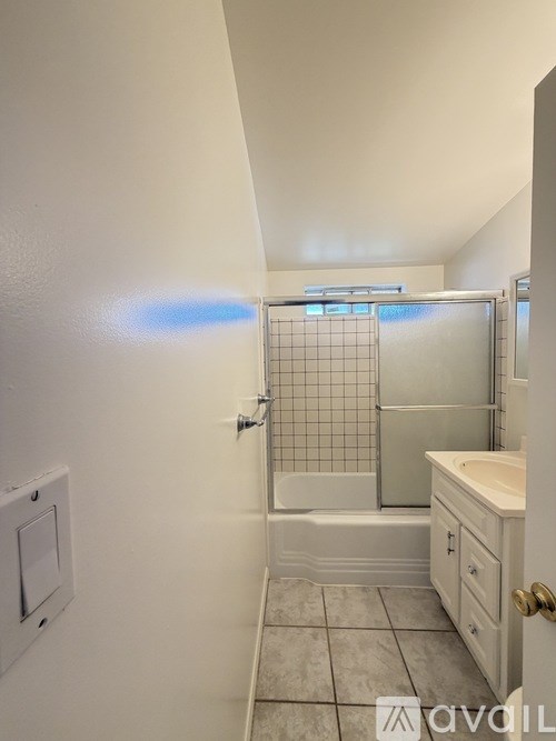 A bathroom with a white tub, sink, and tiled floor.