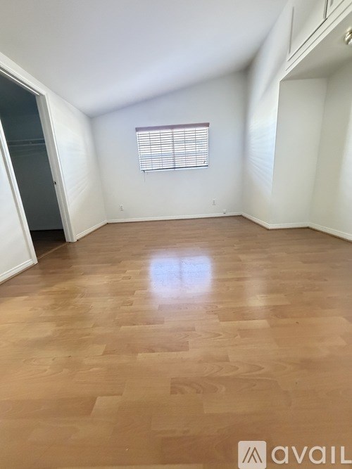 A room with wooden flooring and a window with blinds.