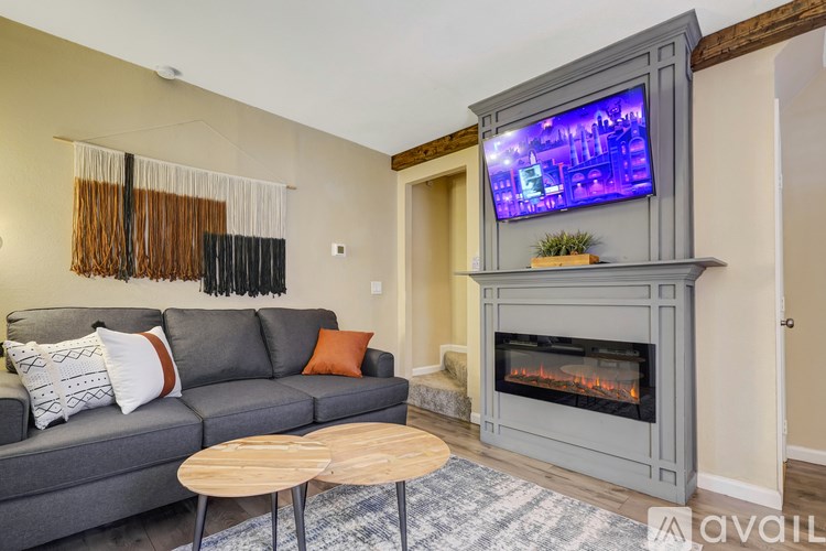 A living room with a grey couch and a television mounted above a fireplace.