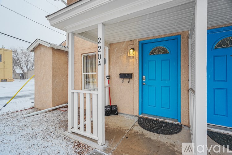 A blue door is on the right side of a house with the number 220A on the wall.