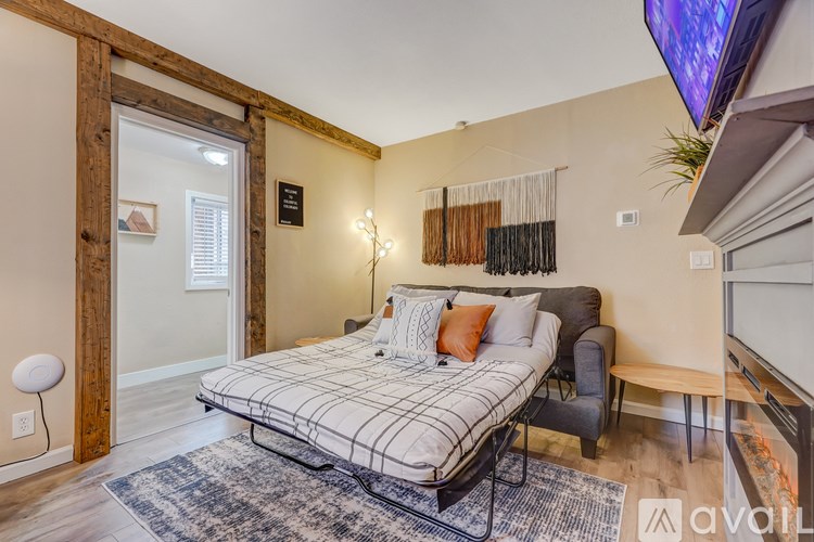 A bedroom with a bed, a chair, and a TV mounted on the wall.