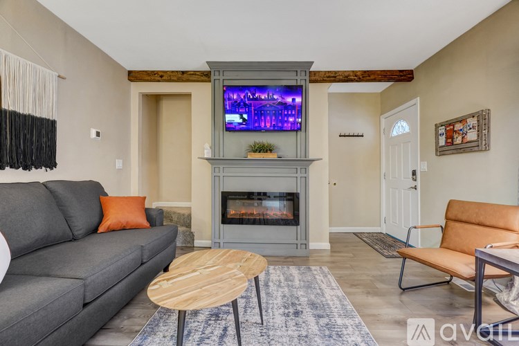 A living room with a grey couch, a wooden coffee table, and a television displaying a purple screen.