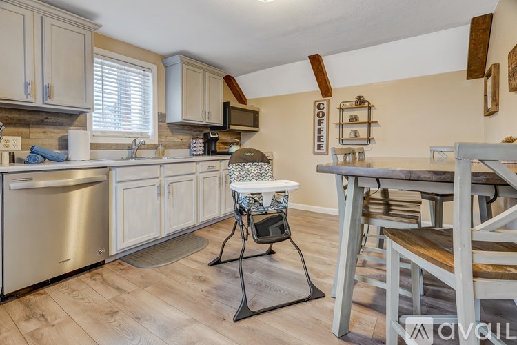 A kitchen with a refrigerator, a microwave, a dishwasher, a sink, a table with chairs, and a coffee sign on the wall.