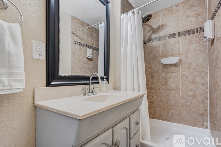A bathroom with a sink, mirror, and shower.
