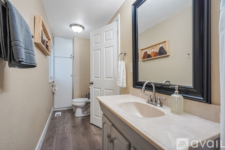 A bathroom with a toilet, sink, mirror, and a towel hanging on the wall.