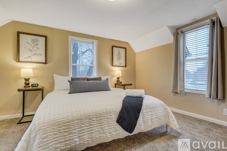 A bedroom with a white bed and two wall lamps.