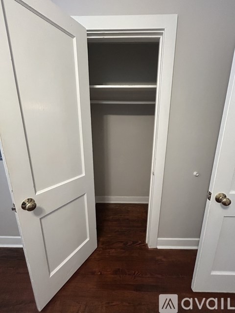 A white door with a gold handle is open to a small closet.