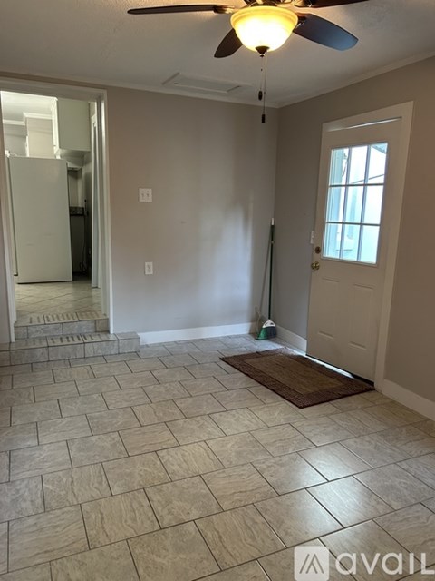 A room with a ceiling fan and tile flooring.